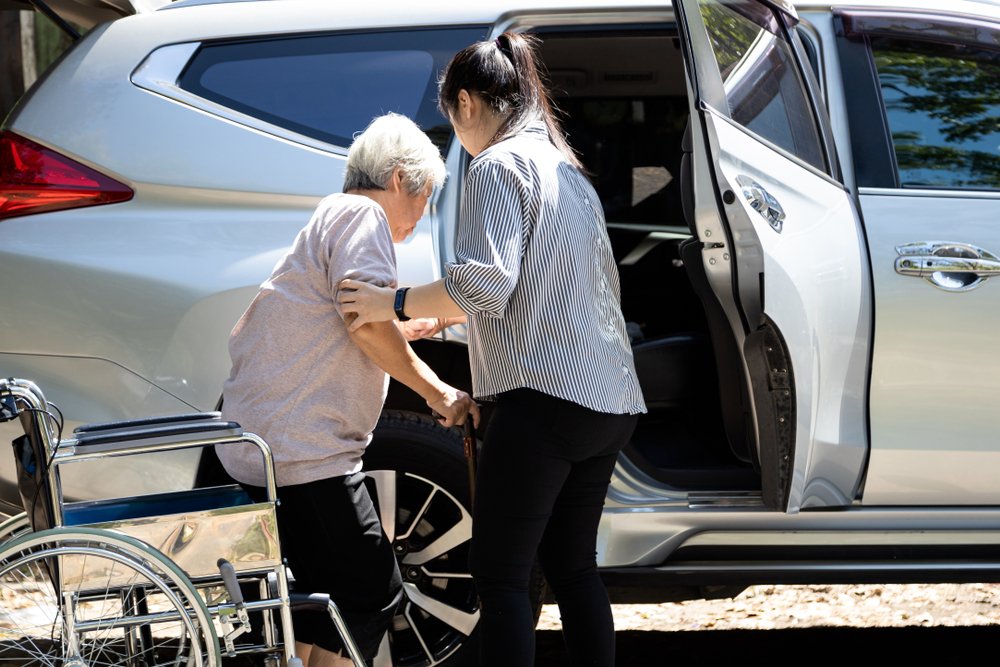Caregiver offering comfort by placing their hand on the hands of a senior man who is holding a cane