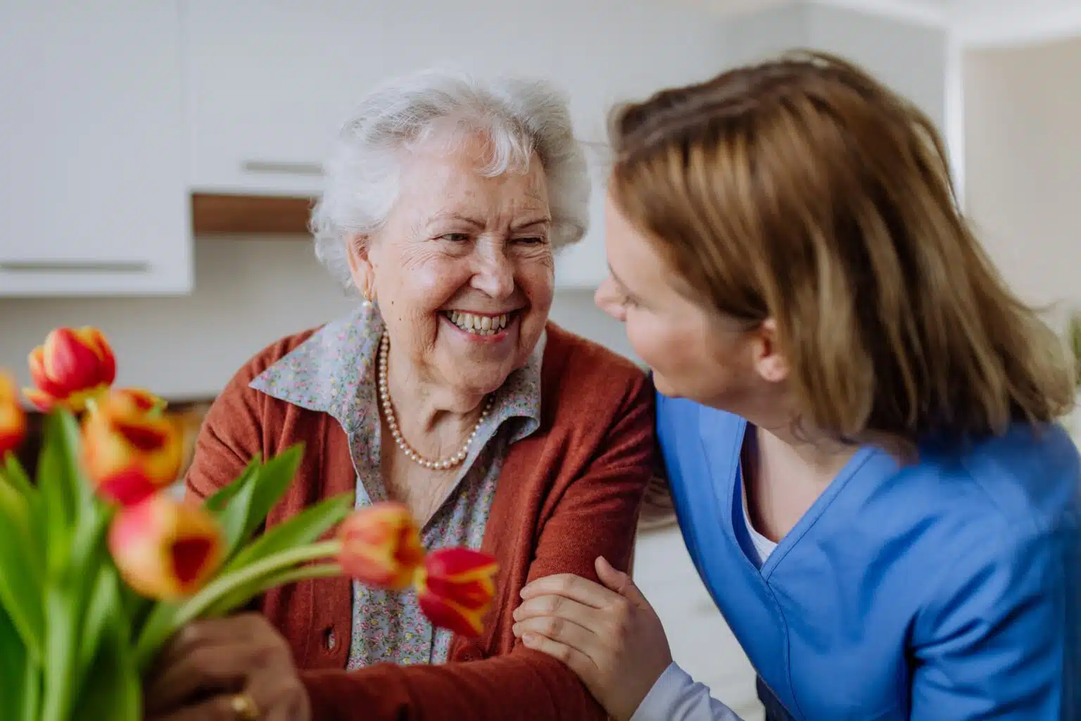 Caregiver offering comfort by placing their hand on the hands of a senior man who is holding a cane
