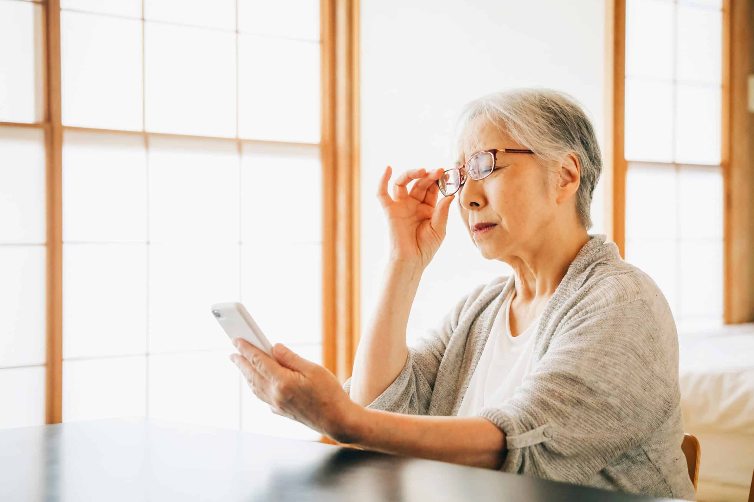 Senior woman trying to read the fine print on her cell phone