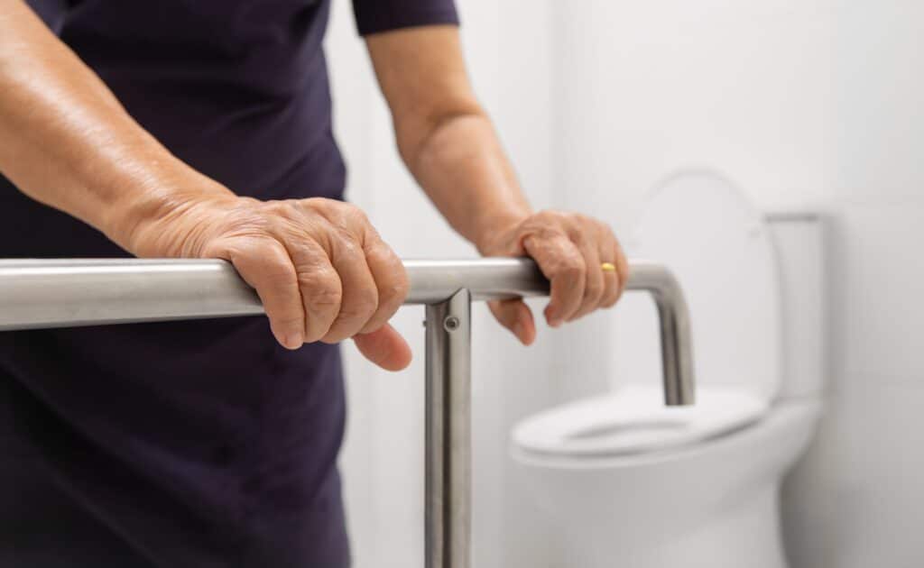 Senior grabbing a grab bar to get up off the toilet