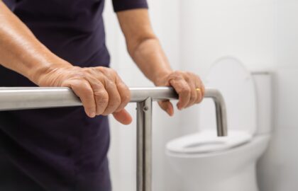 Senior grabbing a grab bar to get up off the toilet