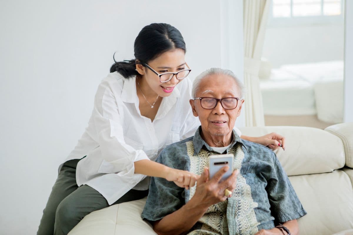 adult daughter showing her aging father how to use a senior-friendly app